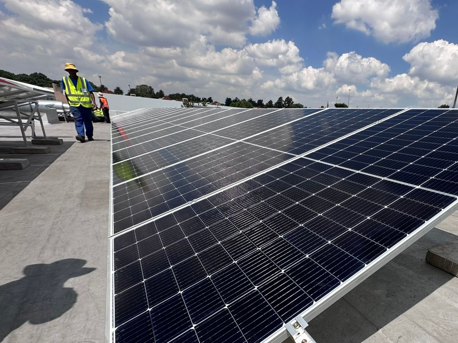 QES installer walking between rows of solar panels on a large rooftop array