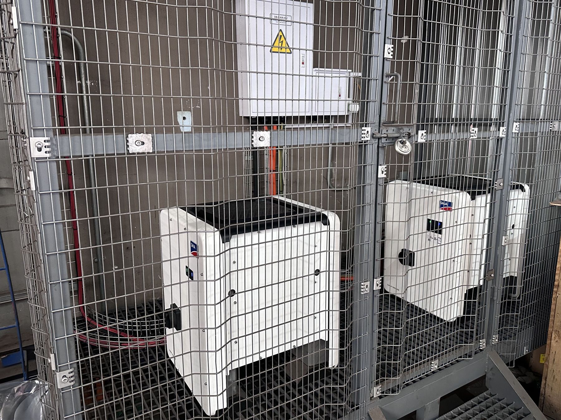 SMA inverters mounted in a secure cage on a commercial site